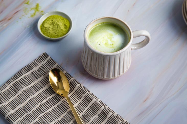 A cup of green tea alongside a bowl of matcha