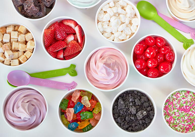 A variety of cups of frozen yogurt and toppings