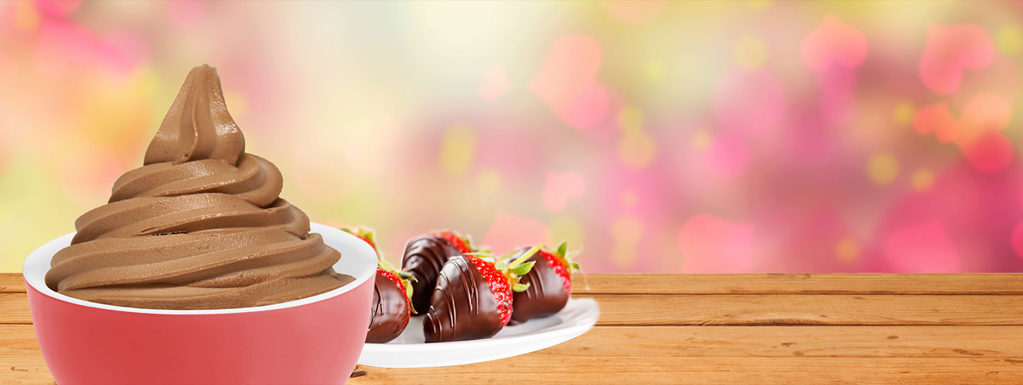 A cup of frozen yogurt alongside chocolate covered strawberries.