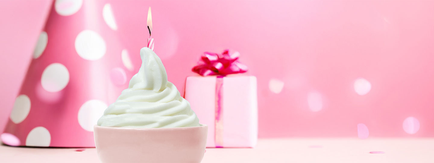 A cup of frozen yogurt alongside a cup of caffe mocha with a stick of peppermint candy.