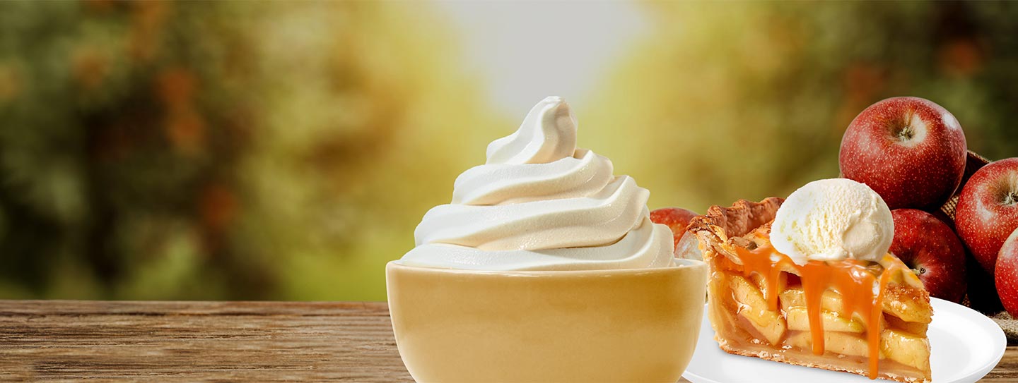 A cup of frozen yogurt alongside apples and a slice of apple pie.